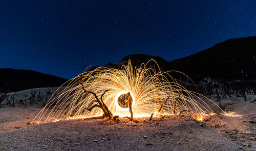 Man standing by wire wool on land at night