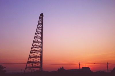 Low angle view of electricity pylon at sunset