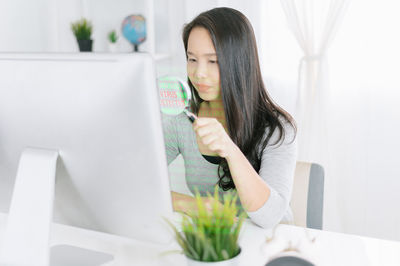 Young woman using phone while sitting on table