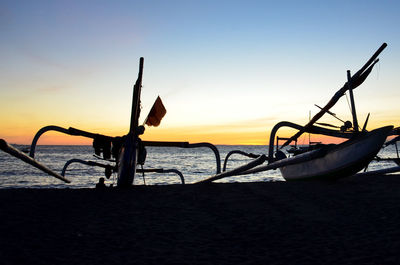 Silhouette boat on beach against sky during sunset