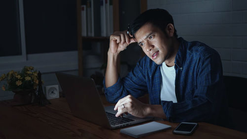 Young man using mobile phone while sitting on table