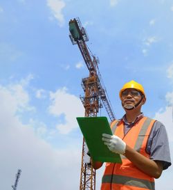 Low angle view of man holding umbrella against sky