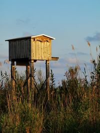 Wooden hut on field against sky