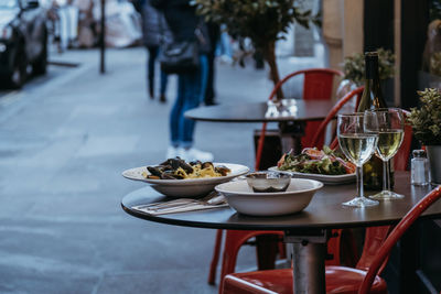 Plates with food and glasses of wine at the outdoor table of a restaurant, selective focus.