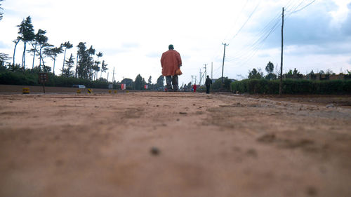 Rear view of man walking on road against sky