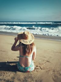 Rear view of man on beach against sky