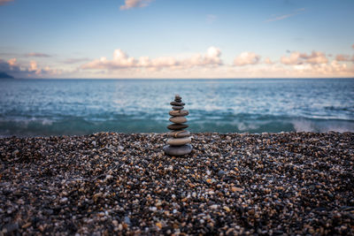 Stack of stones on beach against sky