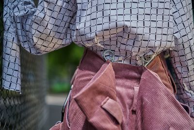 Close-up of clothes hanging on chainlink fence