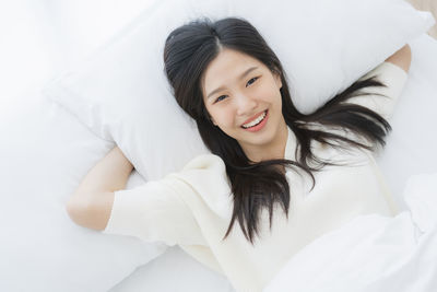 Portrait of smiling young woman relaxing on bed at home