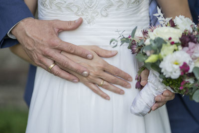 Midsection of couple holding bouquet