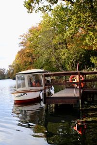 Boat moored by river against sky