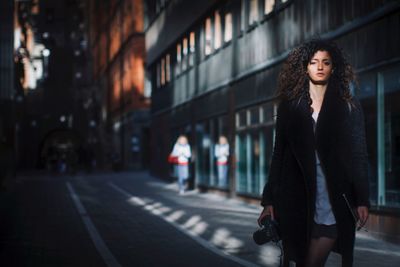 Portrait of woman standing on road in city