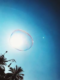 Low angle view of bubbles against clear blue sky