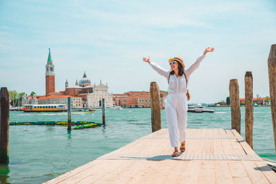 Rear view of woman standing on pier over lake