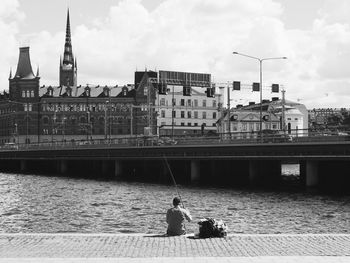 Rear view of man fishing by lake malaren against riddarholm church