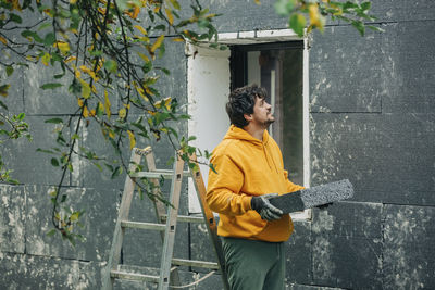 Man holding polystyrene looking at wall of house