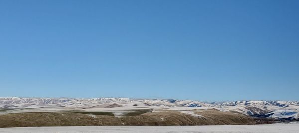 Scenic view of snowcapped mountains against clear blue sky