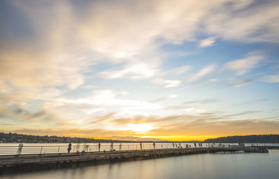 Bridge over river against sky during sunset