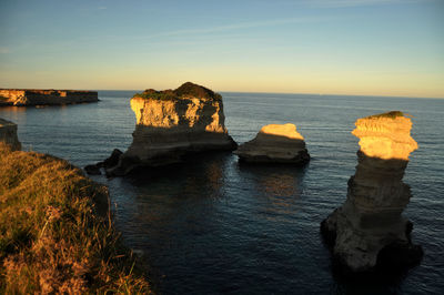 Rock formation on sea against sky during sunset