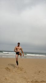 Full length of shirtless boy running on beach