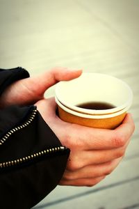 Cropped hand of person holding coffee in disposable cup