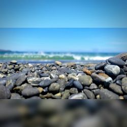 Surface level of pebble beach against blue sky