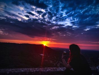 Woman photographing at sunset