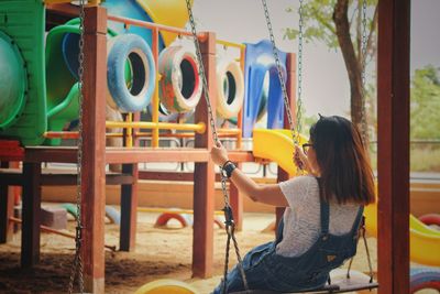 Woman sitting on slide at playground