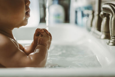 Baby getting sink bath with water drops and rubberband wrists
