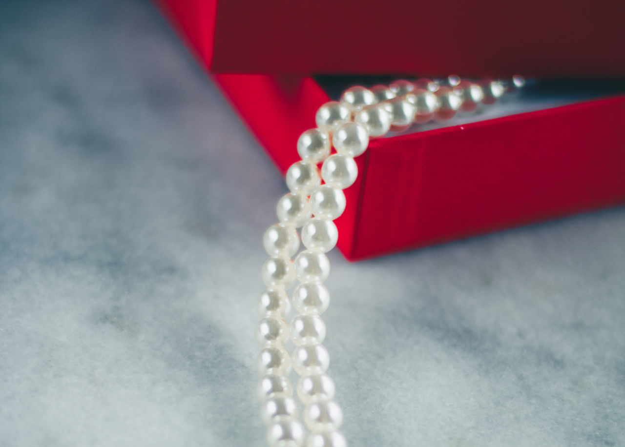 jewelry, necklace, pearl jewelry, wealth, luxury, jewellery, close-up, fashion accessory, indoors, red, fashion, no people, diamond, chain, studio shot, metal, elegance, selective focus, shiny