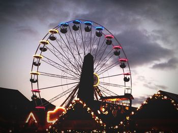 Low angle view of ferris wheel against cloudy sky