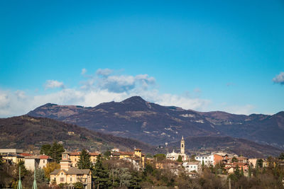 Town by mountains against blue sky