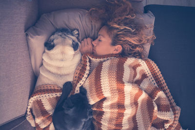 Woman with dogs sleeping on bed at home