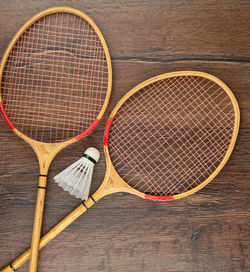Two rackets and a shuttlecock for playing badminton on a wooden background.