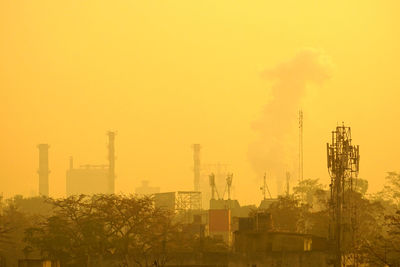 Factory against sky in city during foggy weather