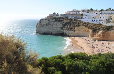 High angle view of beach by rocky cliff against sky