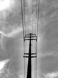 Low angle view of electricity pylon against cloudy sky