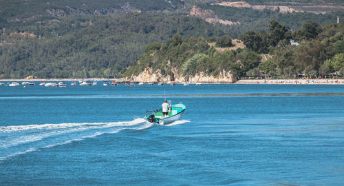 Man riding boat in sea against mountains