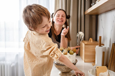 Family fun in the kitchen. mother and son baking carrot cake together. scandinavian kitchen interior