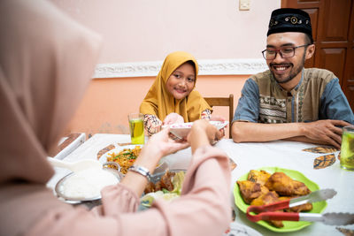 Daughter passing plate to mother at home