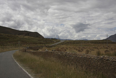 Road amidst field against sky