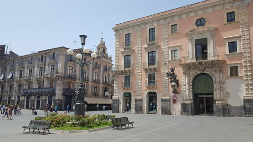 Street by buildings in city against clear sky