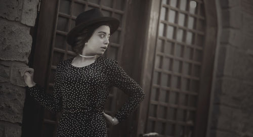 Portrait of young woman standing against wall