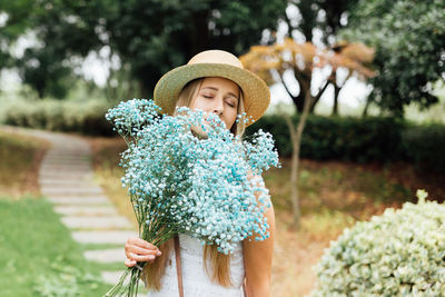 Young woman wearing hat standing against trees