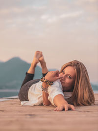 Portrait of woman lying down on land against sky