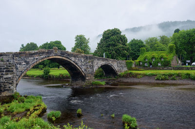 Arch bridge over river against sky