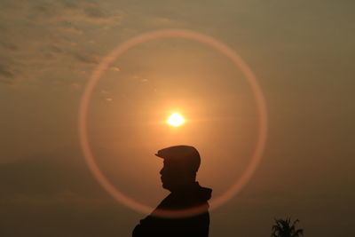 Silhouette man standing at sundog against sky during sunset