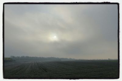 Scenic view of field against cloudy sky