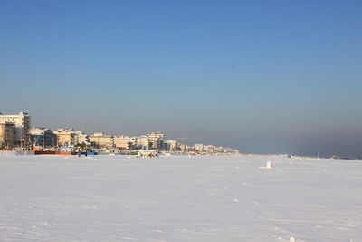 City buildings by sea against sky