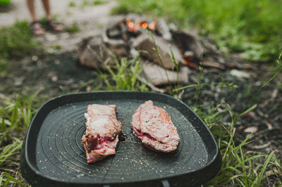 Meat steak is fried in grill pan on gas stove in open air on grass. cooking meal at picnic. healthy